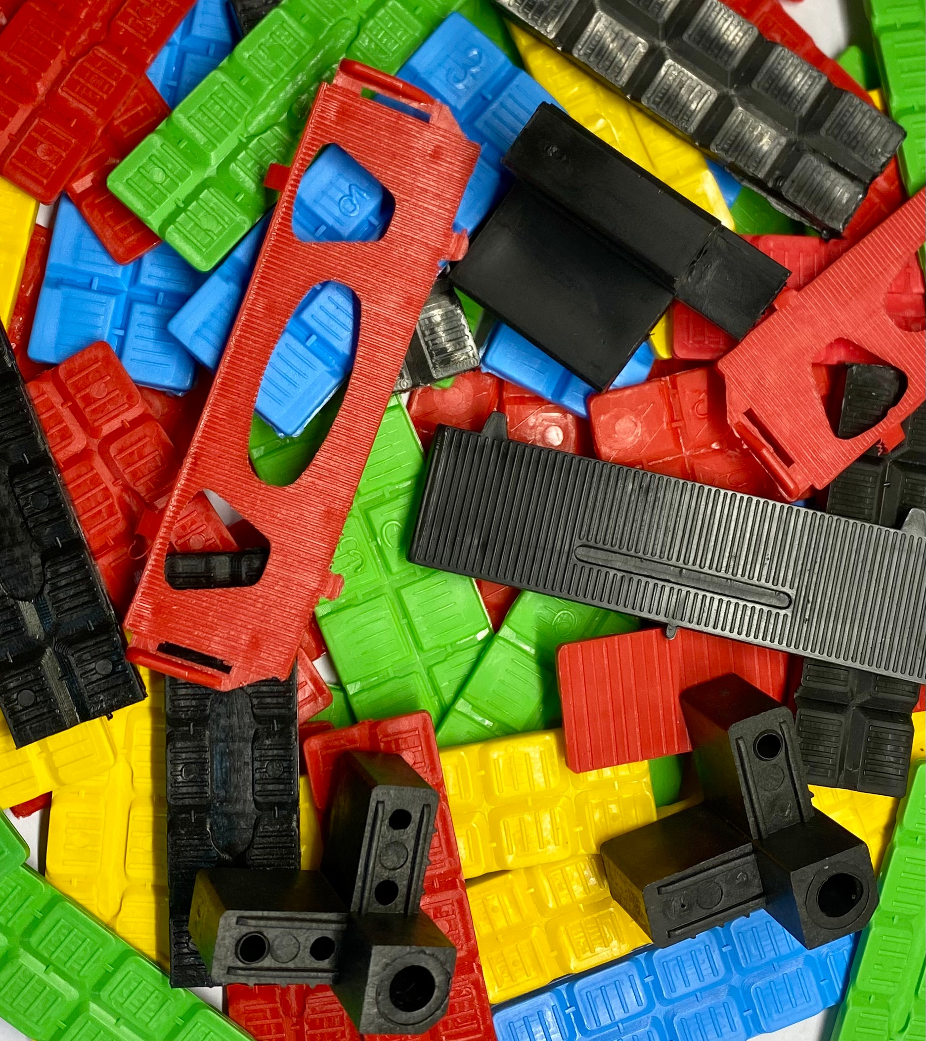 A wide, photographic realism shot of a modern, compact industrial workshop dedicated to precision manufacturing. In the foreground, a sturdy metal worktable holds a selection of shiny calzitos and small hardware for carpentry systems, arranged on a dark anti-slip rubber mat. The walls are lined with neatly organized storage cabinets, labeled bins, and a pegboard with tools, all in neutral grays and blues. A large window on the left brings in soft, natural daylight, complemented by cool LED strip lights along the ceiling, creating an evenly lit, spotless environment. The atmosphere is efficient and trustworthy. Captured from a slightly elevated angle with sharp focus throughout, the image conveys professionalism, order, and more than 30 years of industrial experience without any human presence.